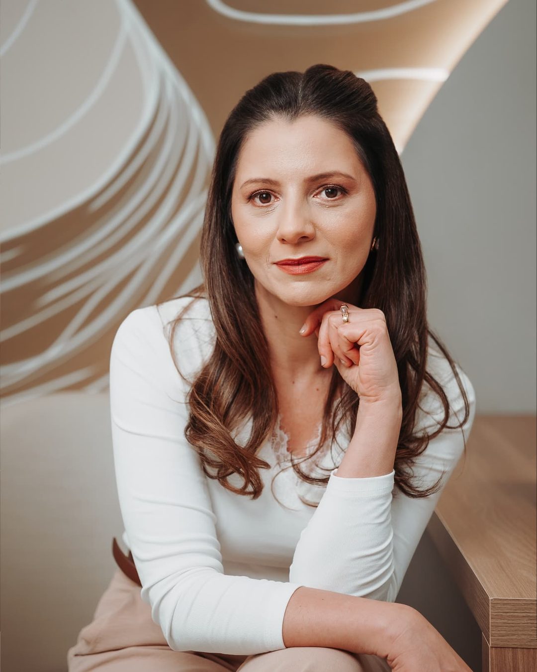 Fabiana Zanuzzo em retrato profissional no consultório, apoiada na mesa de atendimento.