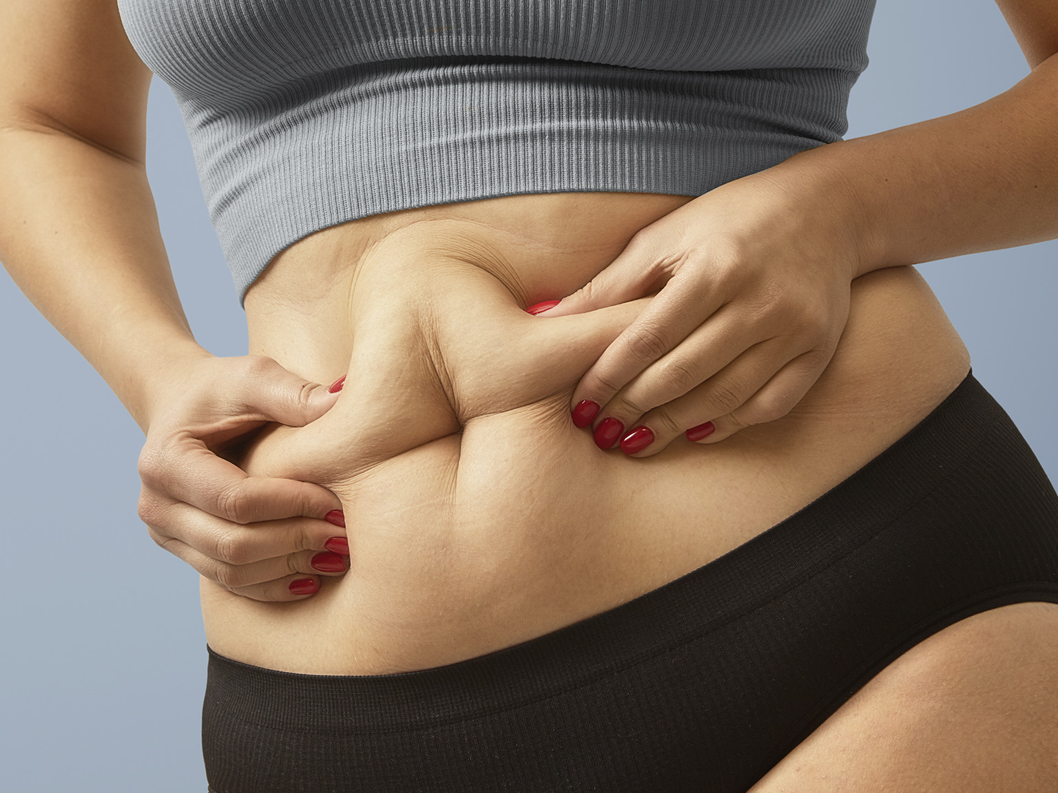 Detalhe da região abdominal de uma pessoa em fundo neutro.