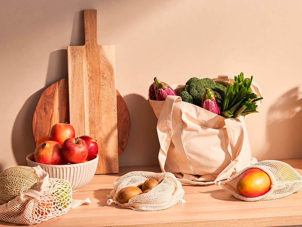 Alimentos frescos, frutas e vegetais organizados sobre uma bancada de madeira.
